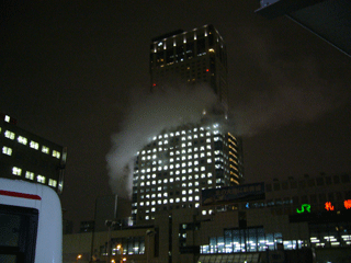 【写真: 煙を上げるJRタワー】
